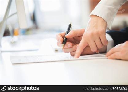 People signing a contract. Detail of a man signing a contract and woman showing where to sign