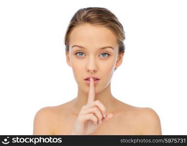 people, silence, secret, gesture and beauty concept - beautiful young woman holding finger on lips