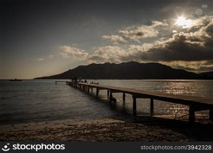 People silhouetted on the jetty at Santa Giulia beach in Corsica