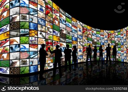 People silhouettes stood in front of a curved wall of screens