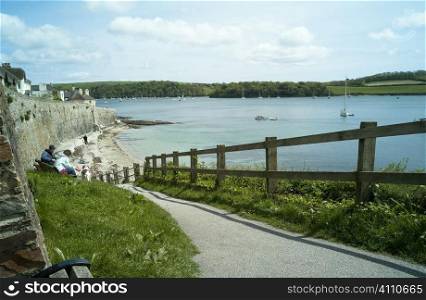 People sit on harbour path, Cornwall