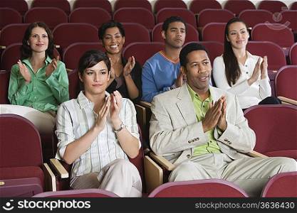 People sitting in auditorium and clapping hands