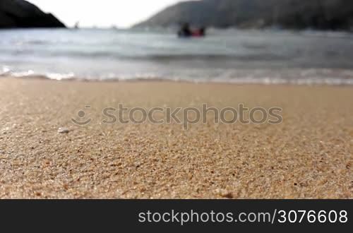 People splashing in sea waves, focus on sand