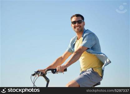 people, sport and lifestyle concept - happy smiling young man in sunglasses riding bicycle outdoors. happy smiling man riding bicycle outdoors