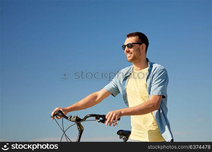 people, sport and lifestyle concept - happy smiling young man in sunglasses with bicycle outdoors. happy smiling man with bicycle outdoors