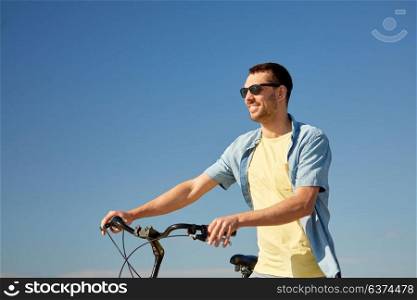 people, sport and lifestyle concept - happy smiling young man in sunglasses with bicycle outdoors. happy smiling man with bicycle outdoors