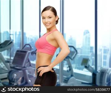 people, sport, fitness and healthy lifestyle concept - smiling sporty asian woman over gym machines background