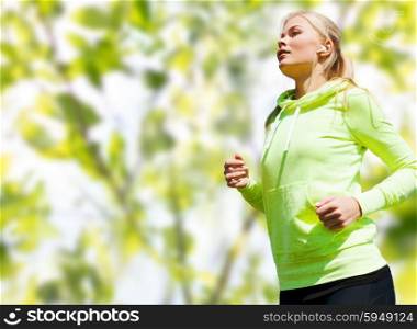 people, sport, fitness and slimming concept - happy woman running or jogging over green leaves background
