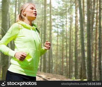 people, sport, fitness and slimming concept - happy woman running or jogging over woods background