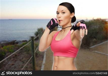 people, sport, fitness, jogging and healthy lifestyle concept - happy asian woman coach blowing whistle outdoors over beach sunset background