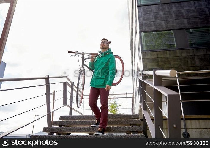 people, sport, style, leisure and lifestyle - young hipster man carrying fixed gear bike on shoulder down stairs in city
