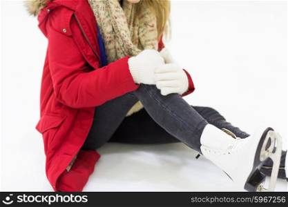 people, sport, trauma, pain and leisure concept - close up of young woman fell down on skating rink with knee injury holding to her leg