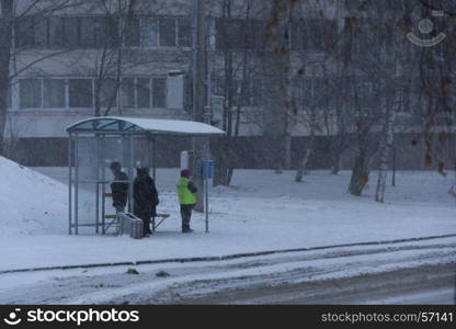 People stand at a bus stop waiting for public transport