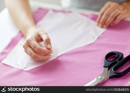 people, stitching, needlework and tailoring concept - tailor woman with paper pattern and chalk drawing on fabric at sewing studio. woman with pattern and chalk drawing on fabric. woman with pattern and chalk drawing on fabric