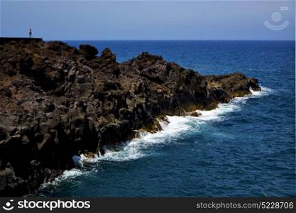 people stone volcanic spain water coast in lanzarote sky cloud beach and summer