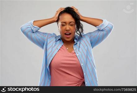 people, stress and despair concept - stressed african american young woman holding to her head over grey background. stressed african american woman holding to head