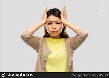 people, stress and despair concept - stressed asian woman holding to her head over grey background. stressed asian woman holding to her head