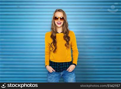 people, style and fashion concept - happy young woman or teen girl in casual clothes and sunglasses over blue ribbed wall background. happy young woman or teen girl in casual clothes