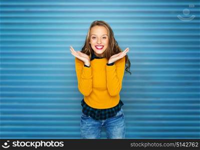 people, style and fashion concept - happy young woman or teen girl in casual clothes having fun over blue ribbed wall background. happy young woman or teen girl in casual clothes