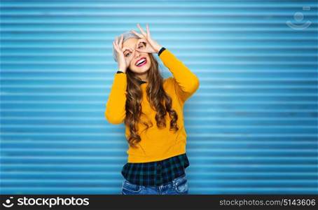people, style and fashion concept - happy young woman or teen girl in casual clothes and hipster hat having fun over blue ribbed wall background. happy young woman or teen girl having fun