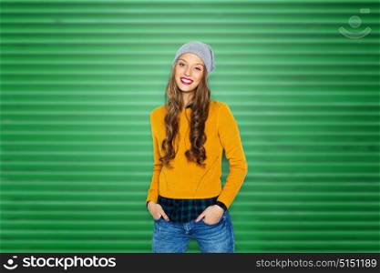 people, style and fashion concept - happy young woman or teen girl in casual clothes and hipster hat over green ribbed wall background. happy young woman or teen girl in casual clothes