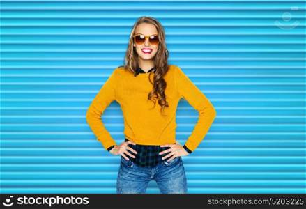 people, style and fashion concept - happy young woman or teen girl in casual clothes and sunglasses over blue ribbed background. happy young woman or teen girl in casual clothes