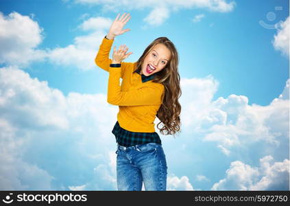 people, style and fashion concept - happy young woman or teen girl in casual clothes having fun and applauding over blue sky and clouds background