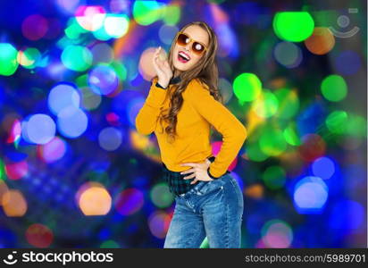 people, style and fashion concept - happy young woman or teen girl in casual clothes and sunglasses having fun over lights background