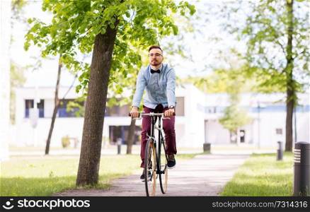 people, style and lifestyle - happy young hipster man riding fixed gear bike on city street. happy young hipster man riding fixed gear bike