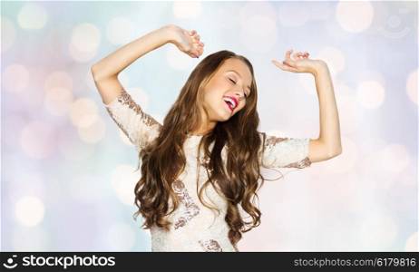 people, style, holidays and fashion concept - happy young woman or teen girl in fancy dress with sequins and long wavy hair dancing at party over holidays lights background