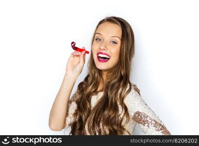 people, style, holidays, celebration and fashion concept - happy young woman or teen girl in fancy dress with sequins and party horn