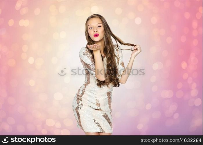 people, style, holidays, hairstyle and fashion concept - happy young woman or teen girl in fancy dress with sequins and long wavy hair sending blow kiss over rose quartz and serenity lights background