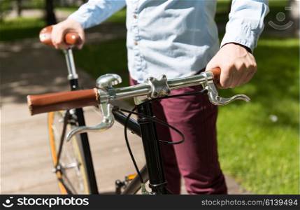 people, style, leisure and lifestyle - close up of young hipster man with fixed gear bike on city street