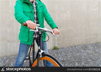 people, style, leisure and lifestyle - close up of young man with fixed gear bike on city street