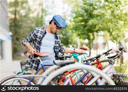 people, style, leisure and lifestyle - hipster man parking fixed gear bike on city street