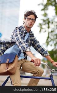 people, style, leisure and lifestyle - young hipster man with shoulder bag and earphones riding fixed gear bike on city street