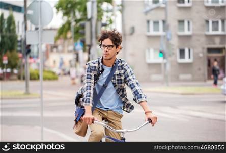 people, style, leisure and lifestyle - young hipster man with shoulder bag riding fixed gear bike on tallinn city street