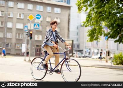 people, style, leisure and lifestyle - young hipster man with shoulder bag riding fixed gear bike on city street