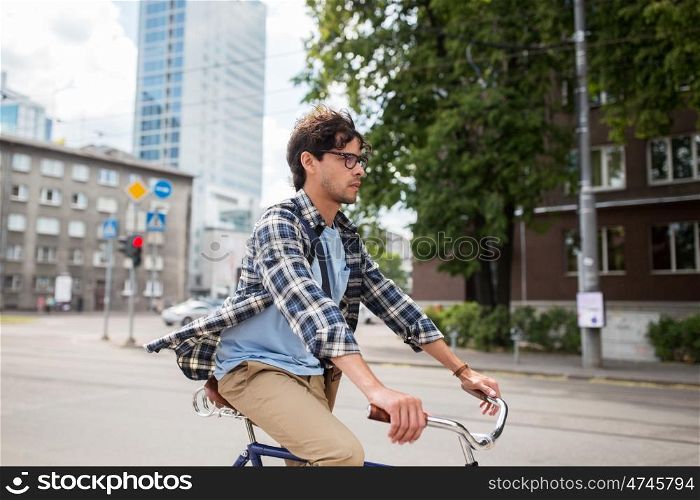 people, style, leisure and lifestyle - young hipster man with shoulder bag riding fixed gear bike on tallinn city street