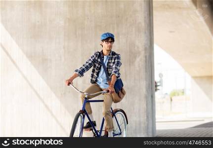people, style, leisure and lifestyle - young hipster man with shoulder bag riding fixed gear bike on city street