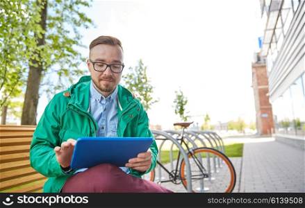 people, style, technology and lifestyle - happy young hipster man with tablet pc computer and fixie bike sitting on bench in city