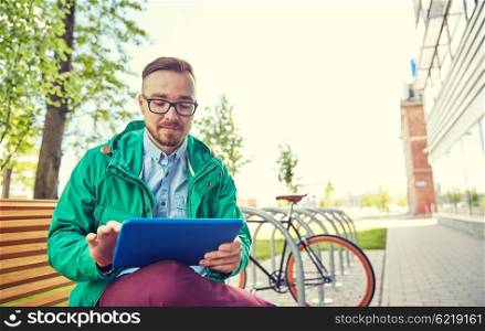 people, style, technology and lifestyle - happy young hipster man with tablet pc computer and fixie bike sitting on bench in city