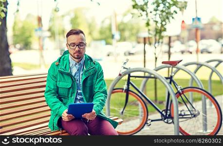 people, style, technology and lifestyle - sad young hipster man with tablet pc and fixie bike sitting on bench in city