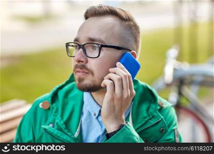 people, style, technology and lifestyle - young hipster man calling on smartphone and sitting on bench in city