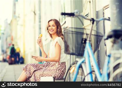 people, style, technology, leisure and lifestyle - happy young hipster woman with smartphone and fixed gear bike eating ice cream on city street