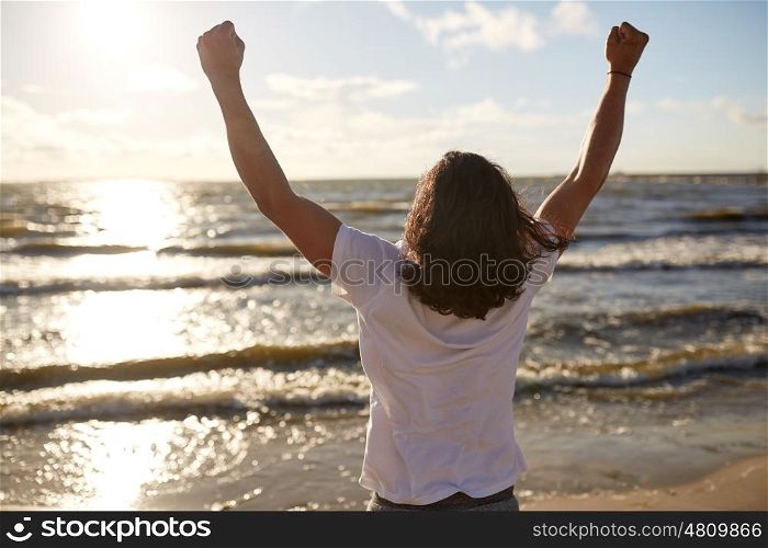 people, success, achievement and power concept - man with rised fist on beach