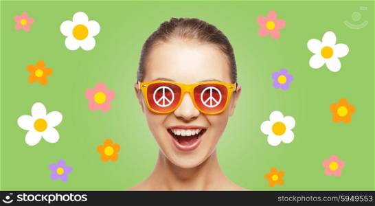 people, summer accessories and pop art concept - happy screaming teenage hippy girl in shades over green background with peace signs nad flowers