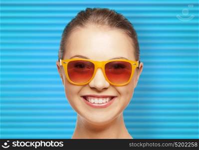 people, summer accessory and eyewear concept - portrait of happy teenage girl or young woman in shades over blue ribbed background. happy teenage girl or woman face in shades