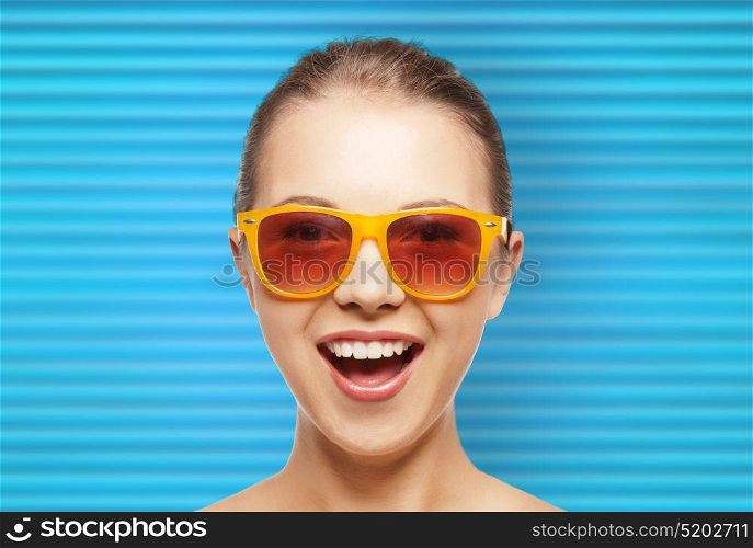 people, summer accessory and eyewear concept - portrait of happy teenage girl or young woman in shades over blue ribbed background. happy teenage girl or woman face in shades