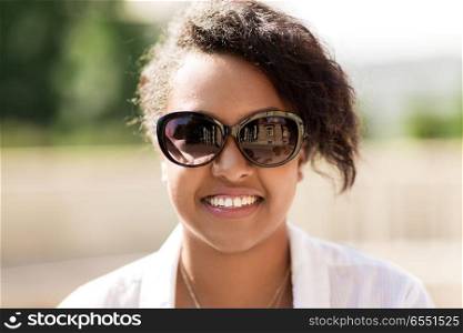 people, summer and eyewear - happy african american young woman in sunglasses outdoors. happy african american young woman in sunglasses. happy african american young woman in sunglasses